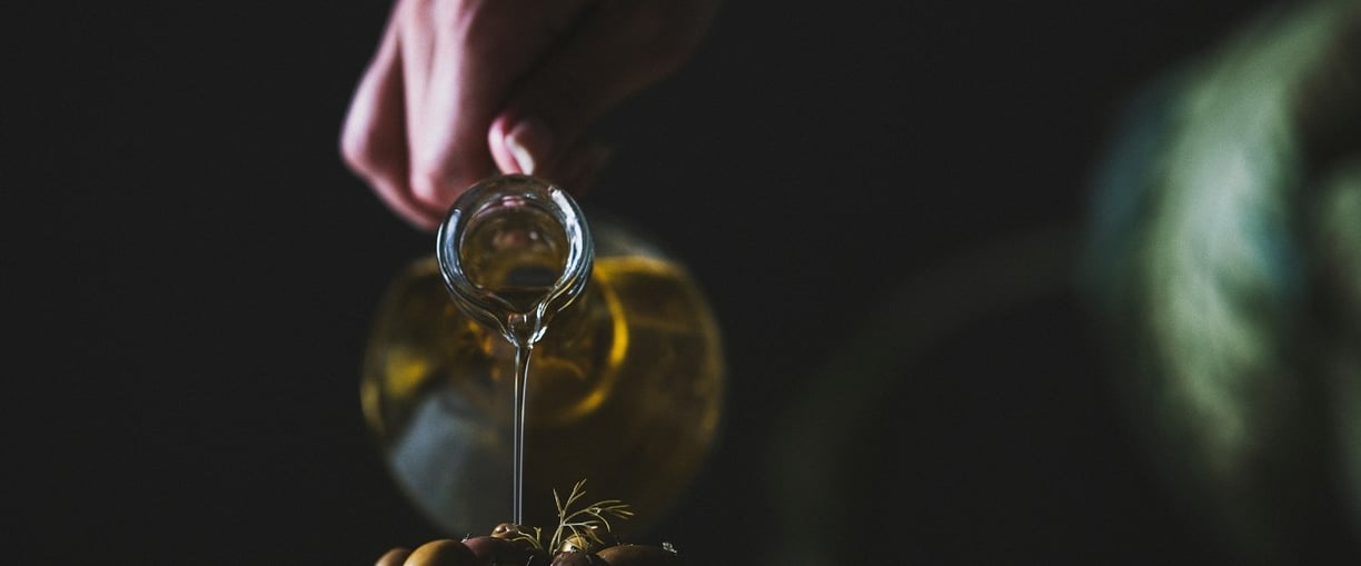a person pouring olives into a bowl of olives