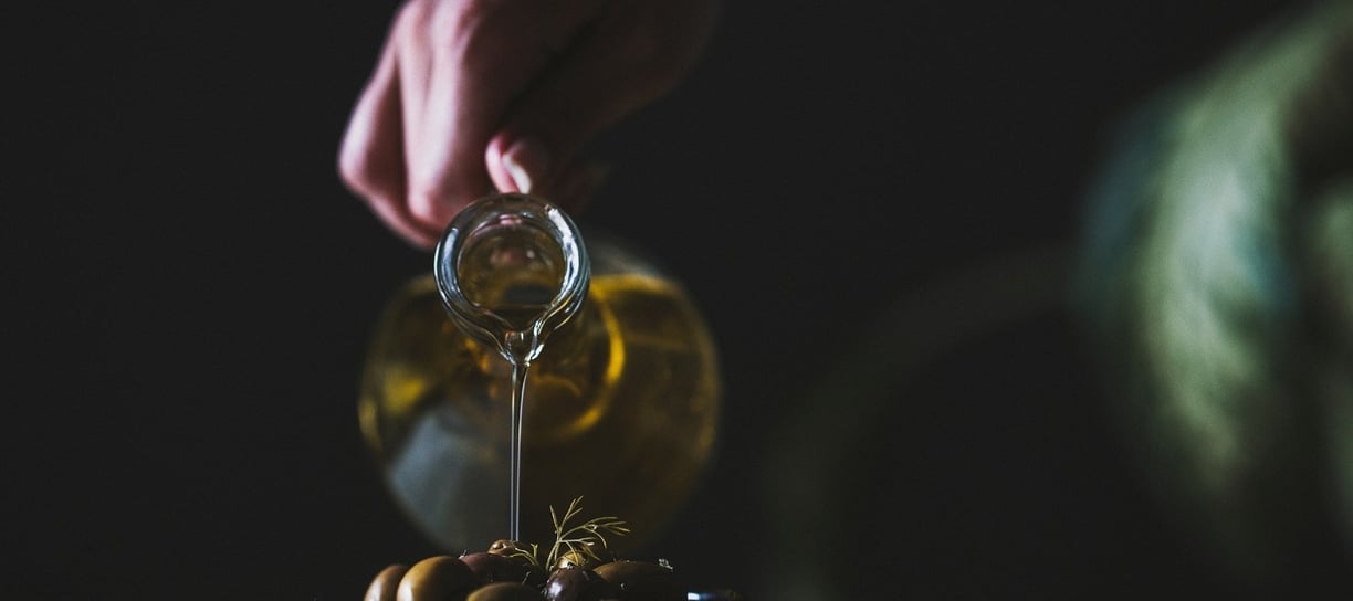a person pouring olives into a bowl of olives